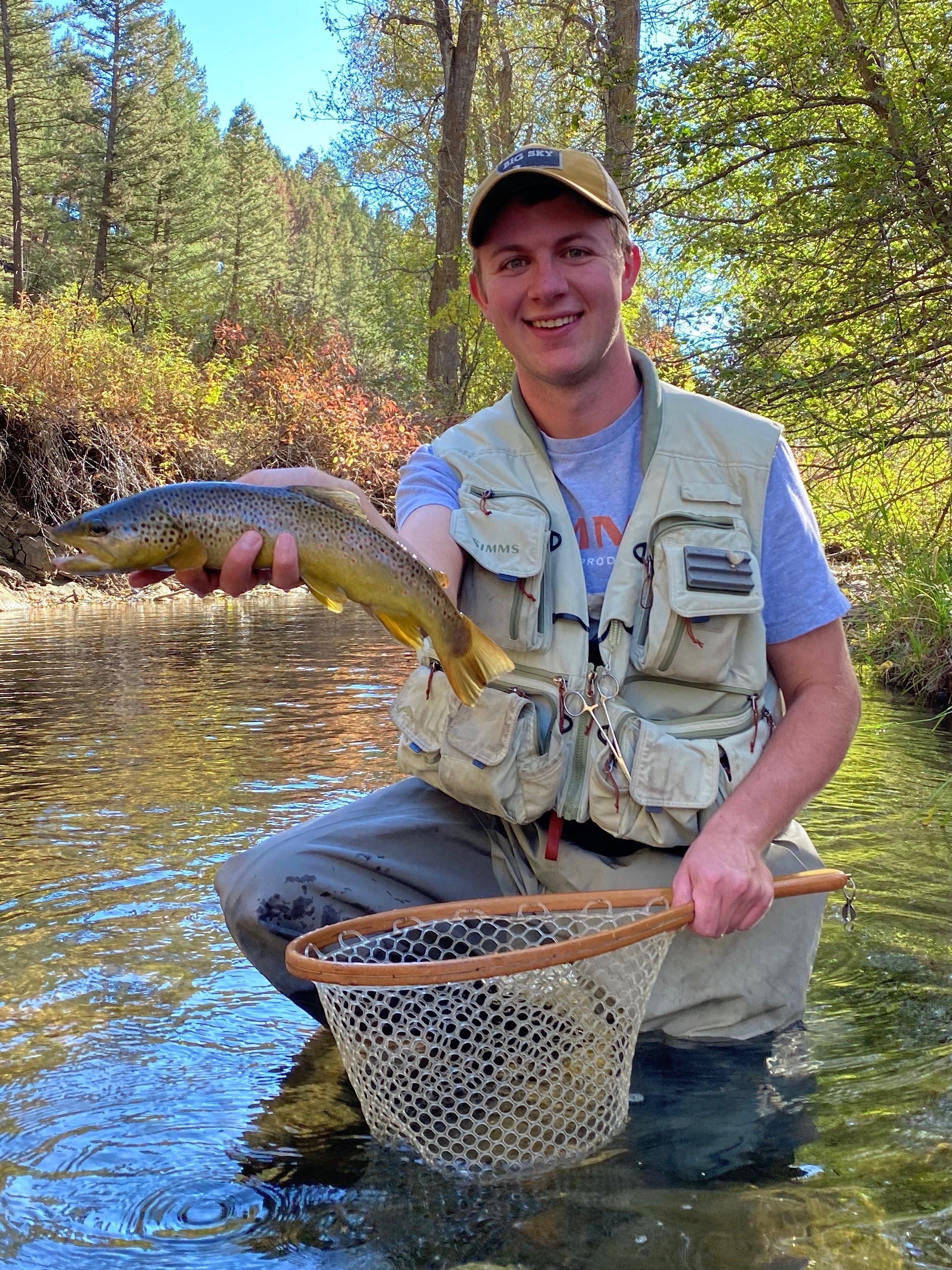 Matt Deyoe posing with a fish in a stream.