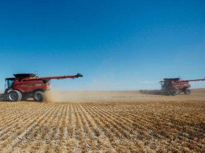 two red farm vehicles on an agricultural field