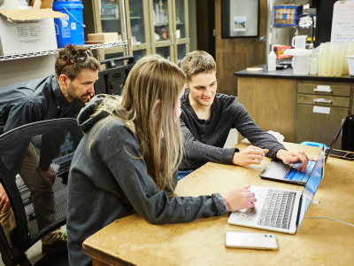 A faculty member overlooks two students looking at research results